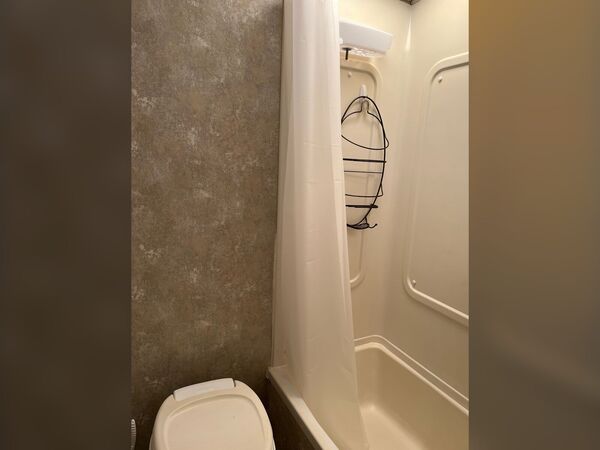 Bathroom with a toilet and a tub-shower with a curtain and a hanging shower caddy