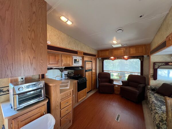 Kitchen with an air fryer oven, sink, propane stove and microwave, opening onto the living area with two recliners and a sofa