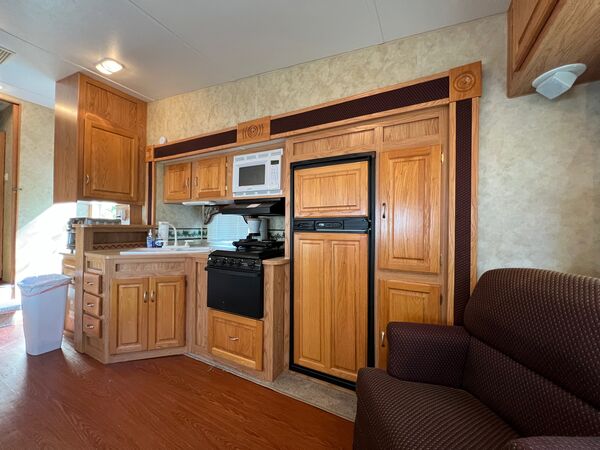 Kitchen with oak cabinets, a sink, propane stove with a microwave above, and a full-height refrigerator