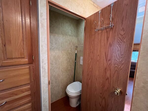 Small toilet room behind an oak door, beside a chest of drawers