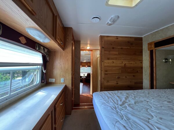 View from the bedroom past the queen bed and dresser counter, down the hall to the living area